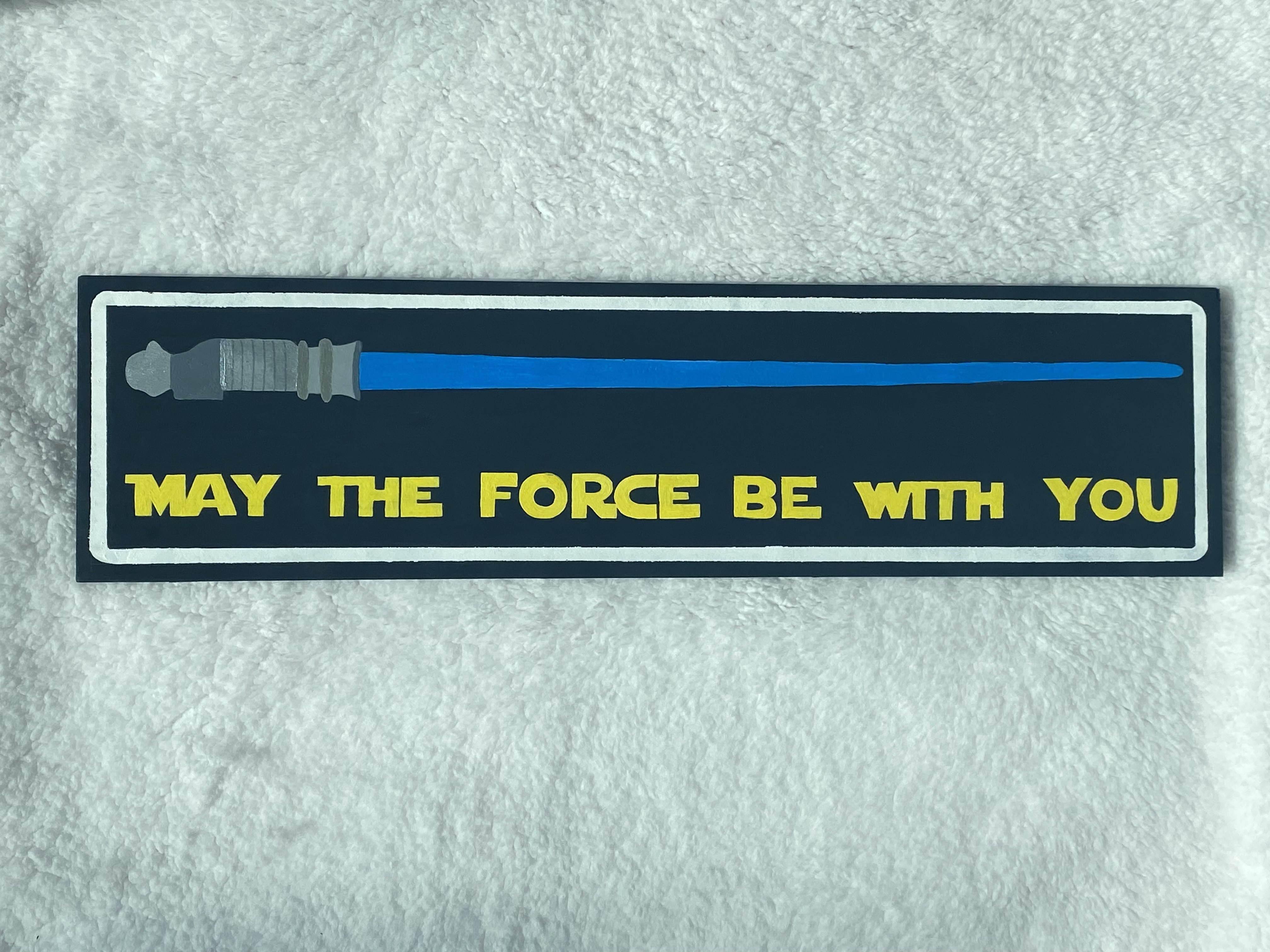 A blue lightsaber with the words May the force be with you in yellow under it.